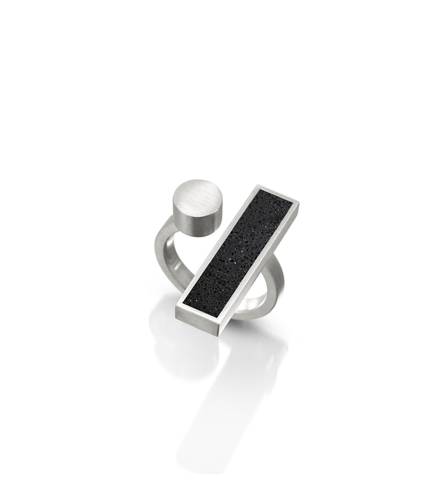 A black concrete ring with a stainless steel bar, part of the Elements Collection, Alma ring, inspired by Bauhaus ethos of art and craftsmanship.