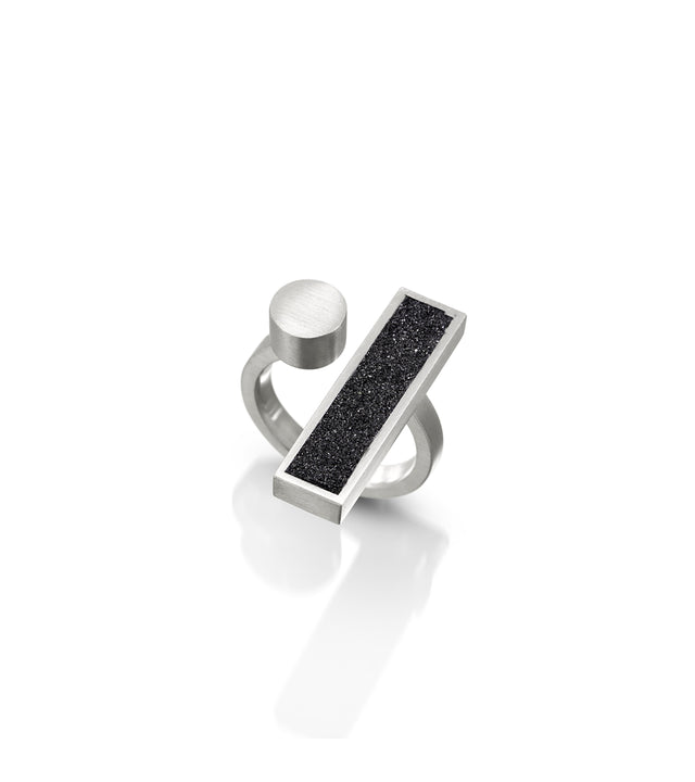 A diamond dust concrete ring with a silver bar, part of the Elements Collection's Alma ring. Inspired by Bauhaus design, it exudes modern elegance and simplicity.