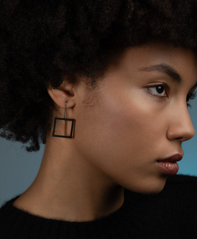 a model wearing simple and minimal black square drop earrings from the KONZUK Artus collection