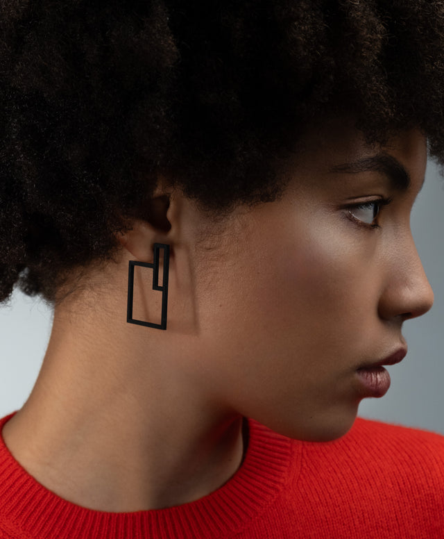 Pair of black geometric statement earrings from the KONZUK Artus collection on a model