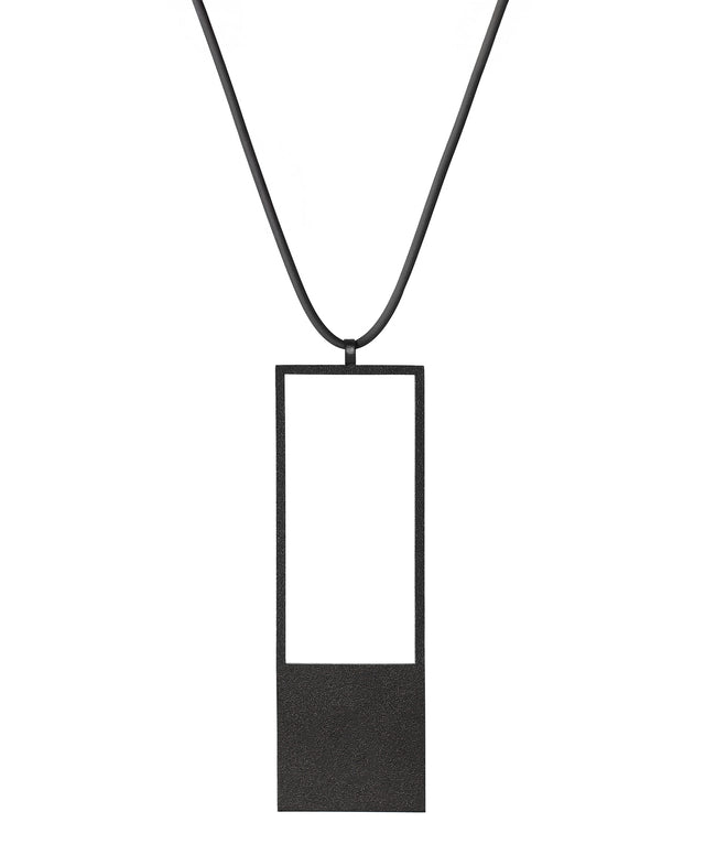 a black minimalist rectangular geometric necklace with a rubber cord from the KONZUK Artus collection Sp2