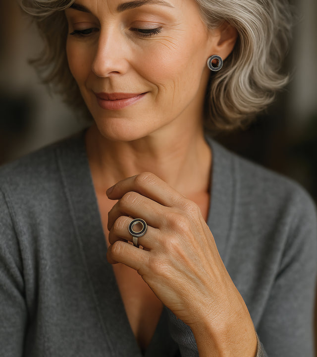 Model wears modern circular stainless steel ring set with concrete and diamond dust.