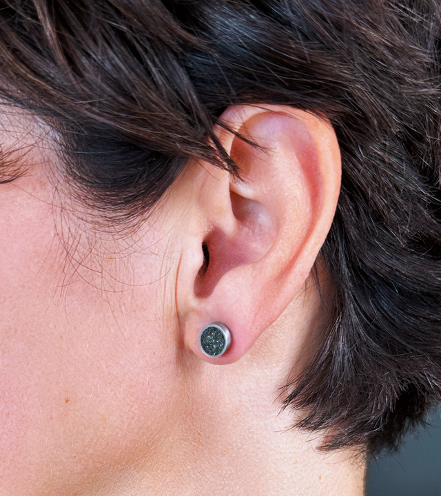 Model's ear showcases the unique minimalist earrings made with stainless steel, concrete, and stainless steel. The designs are tributes to the works of Bauhaus alumni Herbert Bayer.