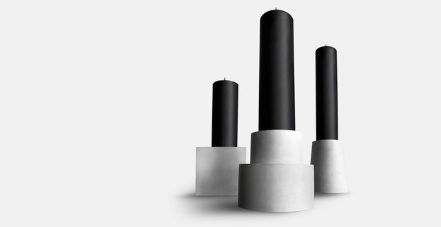 Three geometric concrete based hold black pillar candles.