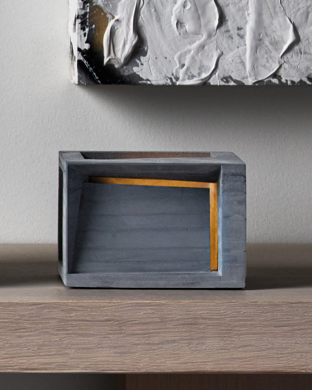 The Pavilion is a minimalist concrete tea light holder that transforms a simple candle into an architectural statement piece. Crafted with layers of raw concrete it casts dramatic light and shadow patterns that create instant ambiance in any room. Its brutalist aesthetic adds sophisticated, gallery-worthy style to your space while providing warm, intimate lighting perfect for relaxation or entertaining. 