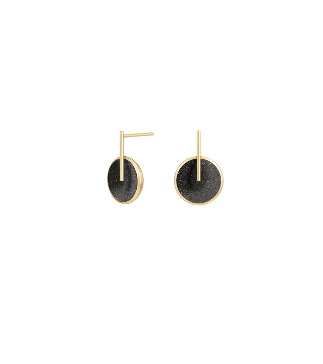 These striking minimalist earrings feature diamond dust-encrusted concrete discs set in warm gold-tone metal with sleek geometric bar posts that create a modern architectural silhouette. The compact design offers comfortable all-day wear while the subtle sparkle of diamond dust against dark concrete adds refined texture that catches the light with every movement.
