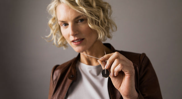 Model wearing round stainless steel locket set with concrete. 