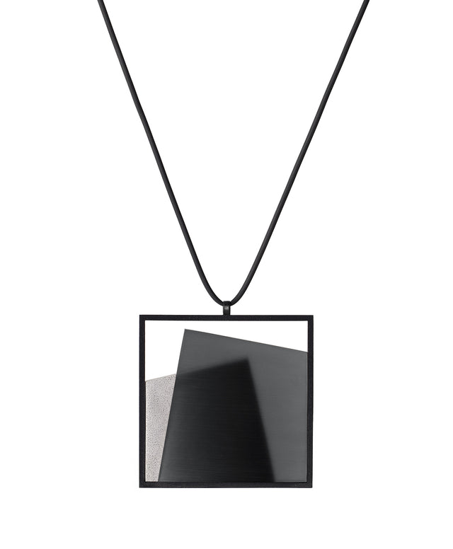 The Astrid necklace in ash grey takes its name from Old Norse, meaning “divinely beautiful,” a reflection of its quiet, sculptural presence. Within the square frame, concrete intersects with resin in a deliberate composition that reveals depth and movement. The meeting of materials creates subtle shifts in tone and surface, drawing the eye to the balance between precision and softness. The Astrid necklace embodies refined minimalism with a sense of calm, architectural beauty.