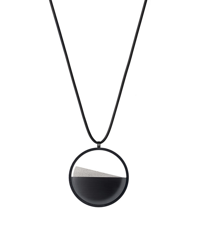The Clara Small necklace in Ash grey resin captures the essence of clarity in a refined, understated form. Named from the Latin clarus, meaning “bright” or “clear,” it reveals a quiet balance between resin and concrete. Within the circular frame, the concrete emerges gently from the resin’s surface, creating a soft meeting of tone and texture. Subtle and luminous, the Clara Small necklace offers a delicate expression of modern minimalism.