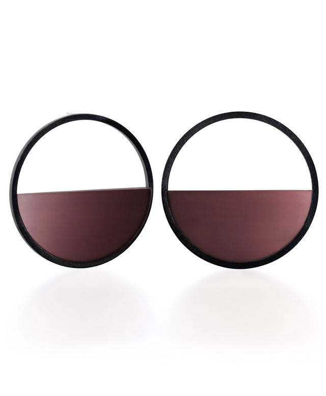 The Sola earrings feature a bold circular form that highlights the depth and tone of cast cognac coloured resin. Larger in scale, they create a sculptural statement while maintaining a sense of balance and simplicity. The smooth surface holds a quiet luminosity that contrasts beautifully with the dark frame, giving the design a modern yet understated presence.