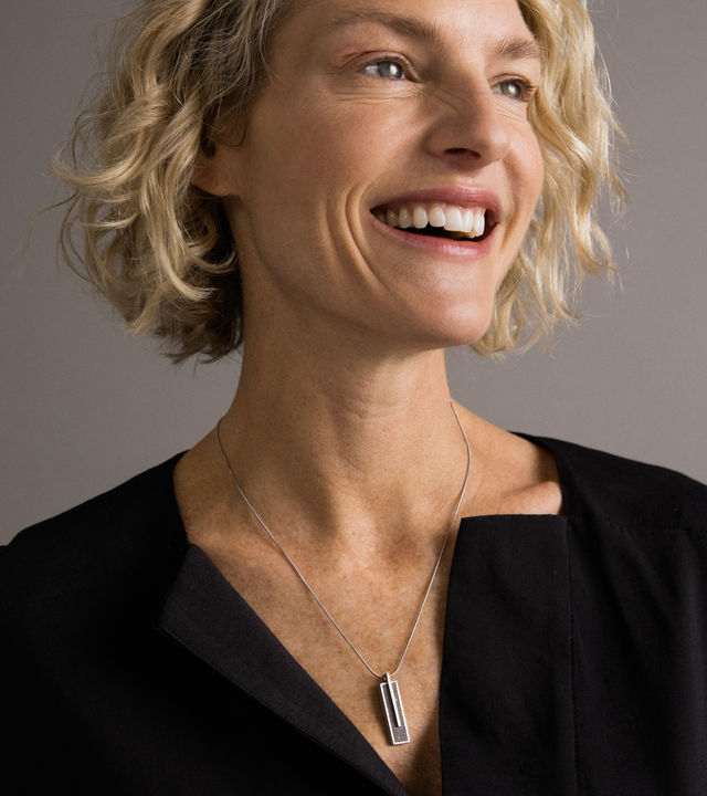Model wearing Memento Beholden pendent with concrete set into small rectangular stainless steel design.