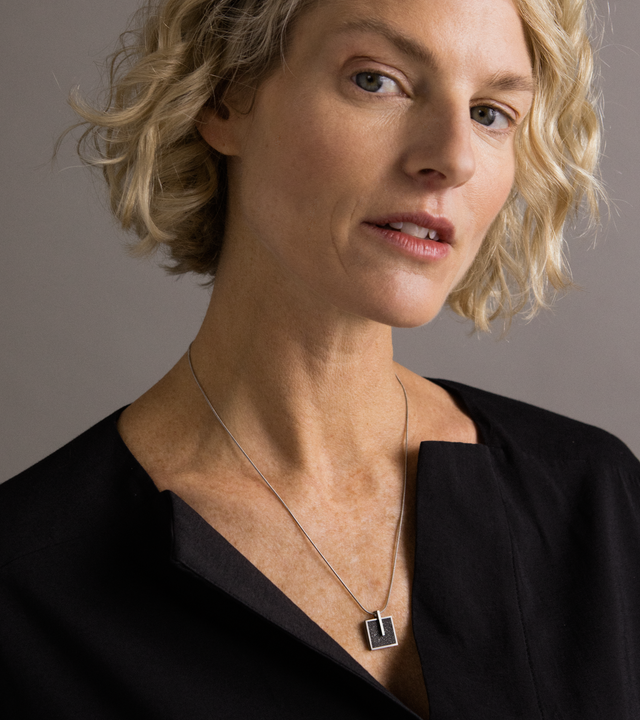 Model wearing Memento Mindful pendent with diamond dust concrete set into small square stainless steel design.
