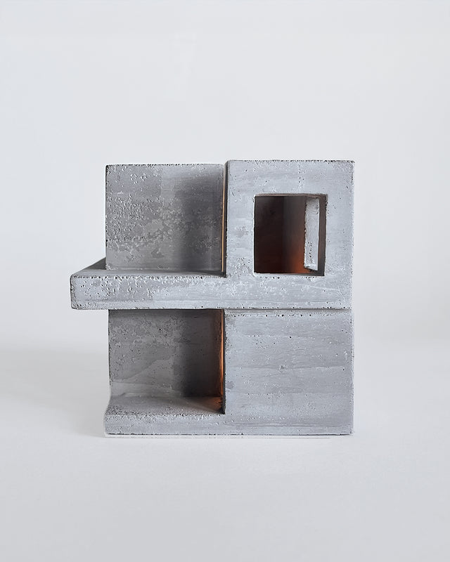Minimalist concrete architectural sculpture with intersecting rectangular forms and cutout openings. Light gray finish with natural texture detail. Part of Habitat series collaboration with Synthesis Design.