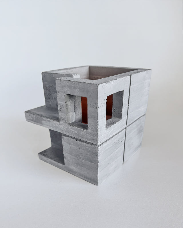 Brutalist-inspired concrete planter with architectural design featuring layered cubic forms, window-like openings, and cantilevered elements. Light gray textured finish with visible seam details. Part of Habitat series collaboration with Synthesis Design.