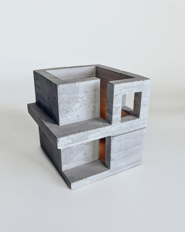 Architectural concrete tealight holder with geometric cutouts and stacked cube design. Light gray with natural texture. Part of Habitat series collaboration with Synthesis Design.