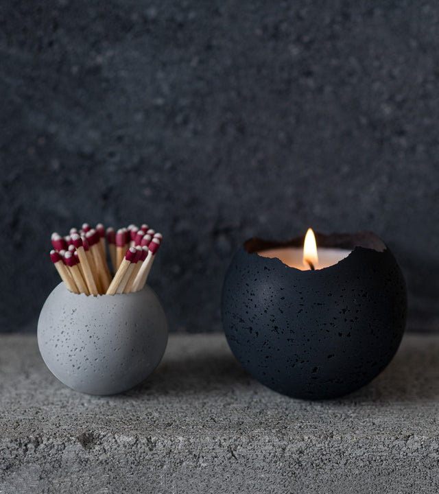 two orbis concrete vessels and a candle holding matches
