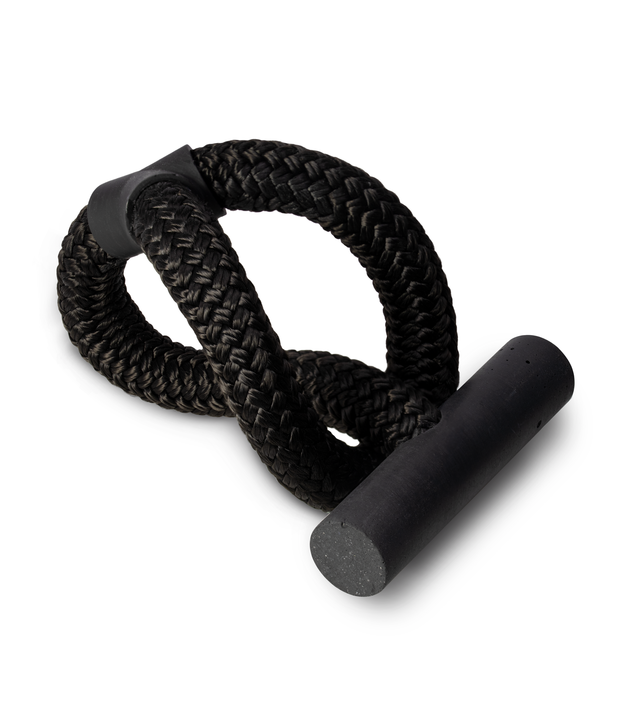 A contemporary concrete bracelet. Featuring a black-tinted concrete pillar fastened to a black double-braided nylon rope. Representing connectedness.