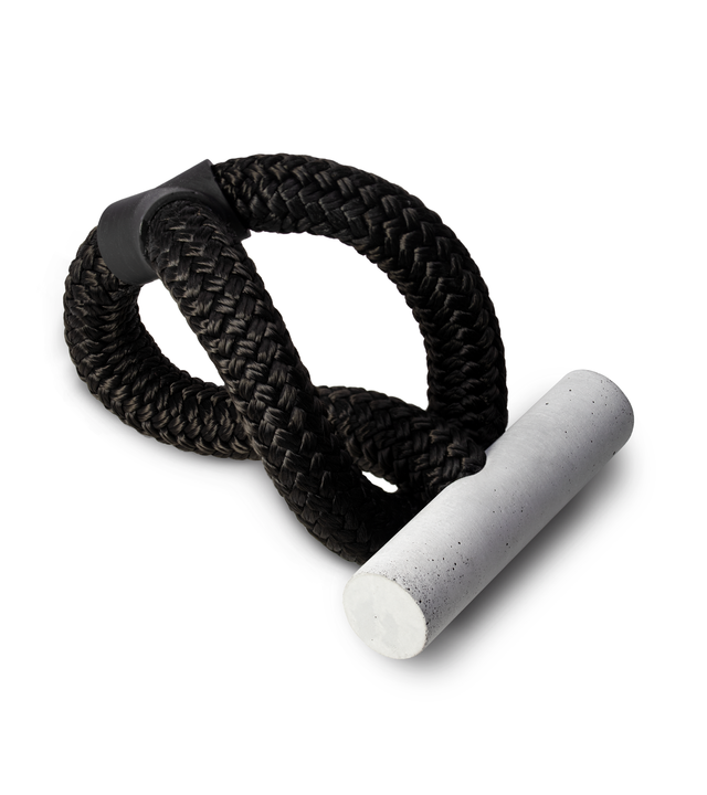 A concrete pillar fastened to a black circular double-braided nylon rope depicts connectedness in a disengaged/dissociated world.