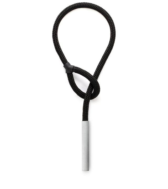 Natural concrete pillar suspended from a double-braided black nylon rope that threads through the loop over to the other side.