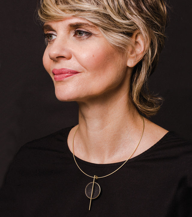 The sparkle of diamond dust infused concrete lines a solid 14 karat gold dome intersected by a thin vertically orientated gold post.