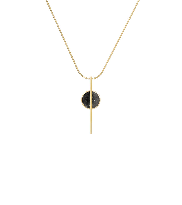 The Linnea Minor 14k necklace features black concrete and the sparkle of embedded diamond dust set into a 14 karat gold dome intersected by a steel post and suspended by a gold cable.