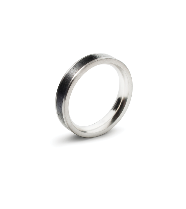 A unique wedding ring with a thin strip of black concrete is set in between stainless steel band.