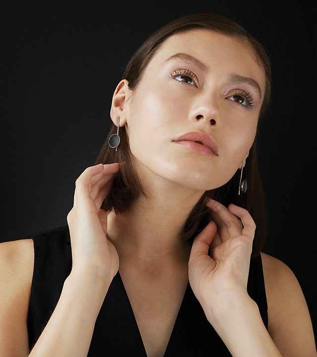Bauhaus inspired Inspira earrings sparkle with diamond dust and black concrete set into a stainless steel dome architecturally suspended on top of a minimalist steel post.