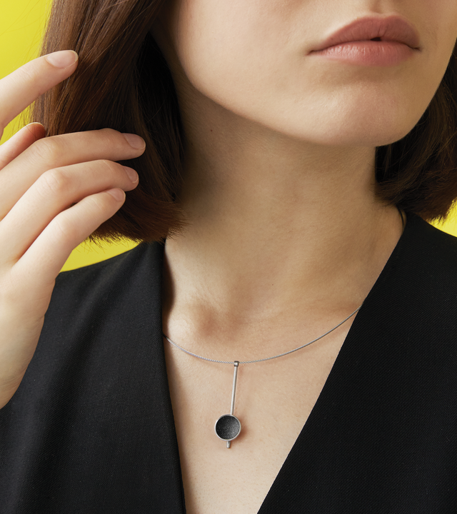 Bauhaus inspired Inspira necklace sparkle with diamond dust and black concrete set into a stainless steel dome architecturally suspended on top of a minimalist steel post.