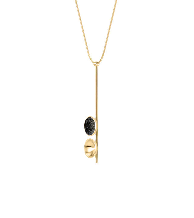 Side view of the modern Freya Minor necklace features two double solid 14 karat gold domes, one lined with diamond dust infused black concrete both architecturally supported an elegant hanging 14k gold post.