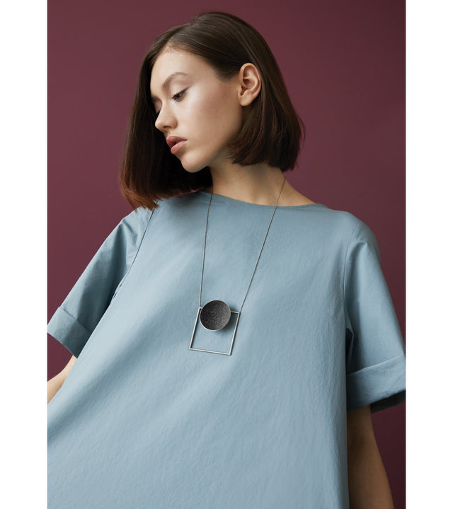 Architectural necklace combines the geometry of a large stainless steel dome lined with the sparkle of diamond dust encrusted concrete suspended onto a minimalist steel square frame.