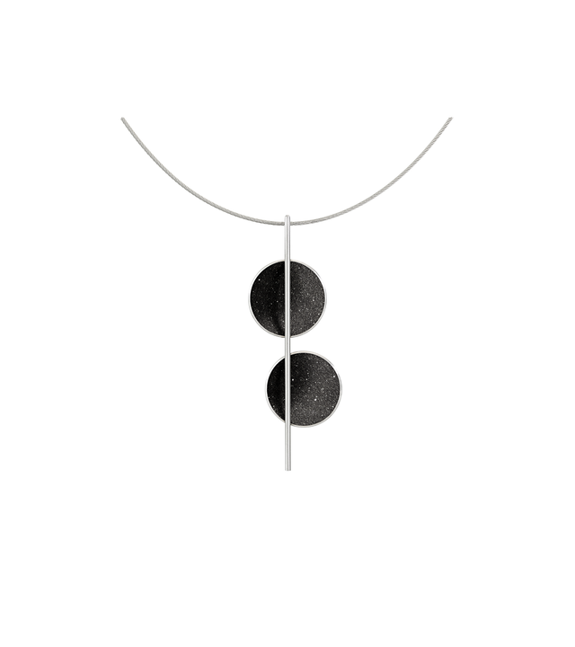 The minimalist Arago necklace sparkles with diamond dust infused black concrete set into two stainless steel domes and architecturally suspended onto an intersecting steel post and cable.