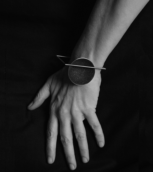 The minimalist Frama Major bracelet sparkles with diamond dust and black concrete set into a stainless steel dome architecturally suspended inside a steel square frame.