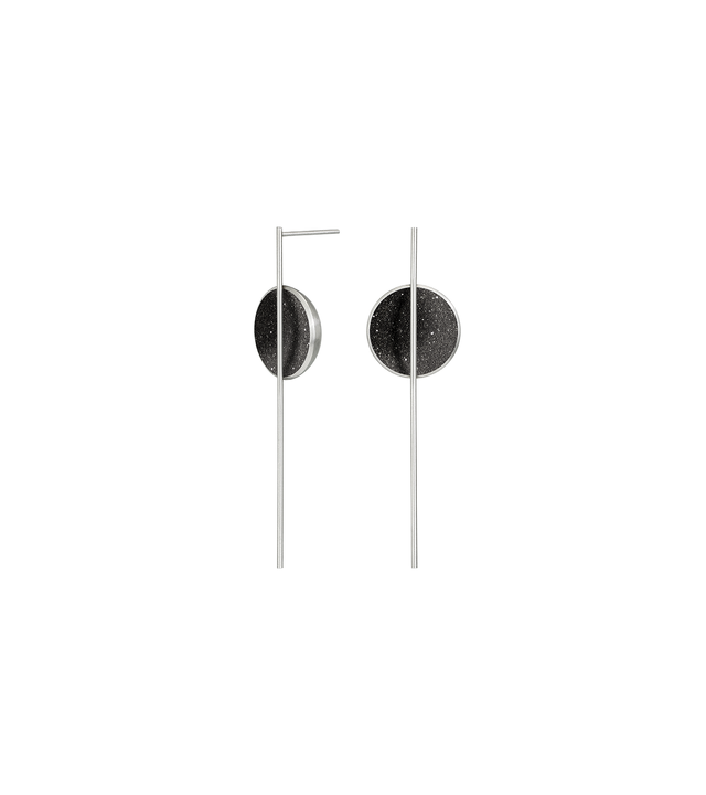 The Infini earrings sparkles with diamond dust and black concrete set into a stainless steel dome architecturally suspended behind a minimalist steel post.
