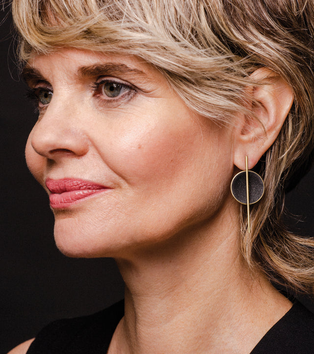 Modern jewelry featuring concrete and diamond dust set into a solid 14 karat gold dome architecturally suspended off centered from a vertically orientated gold post.