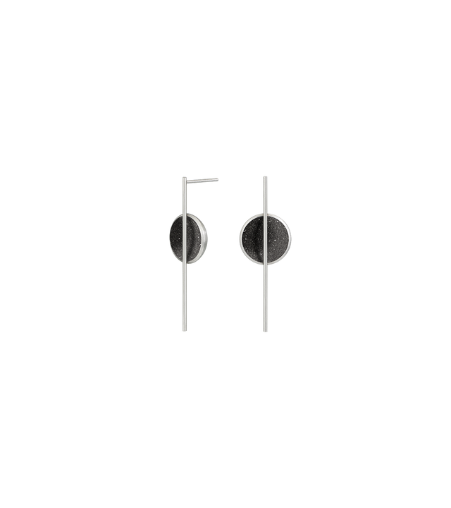 The minimalist earrings Linnea Minor sparkle with diamond dust and black concrete set into a stainless steel dome architecturally suspended from an elegant steel post.