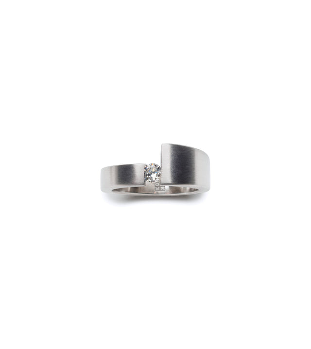 a diamond sits suspended between different width bands in this unique engagement ring