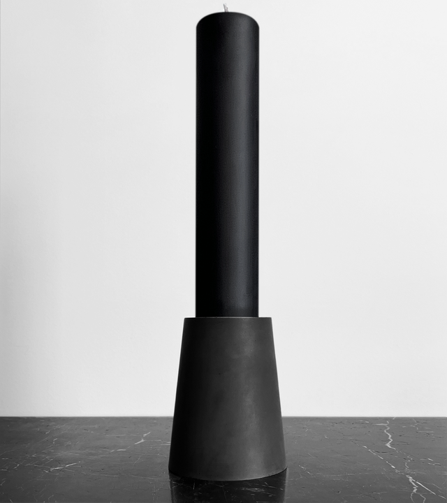 This brutalist-inspired candle holder is crafted from solid concrete, showcasing a minimalist, architectural form that highlights the beauty of raw materials. Made from concrete and black beeswax