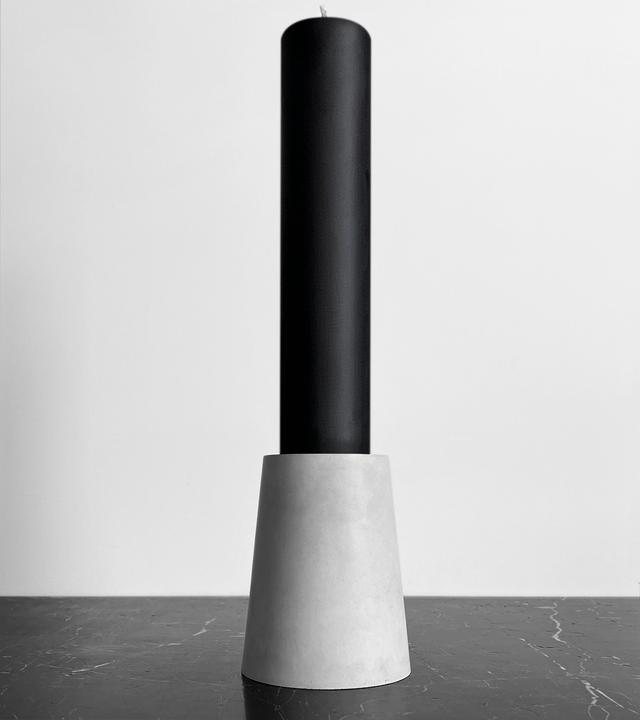 This brutalist-inspired candle holder is crafted from solid concrete, showcasing a minimalist, architectural form that highlights the beauty of raw materials. Made from concrete and black beeswax