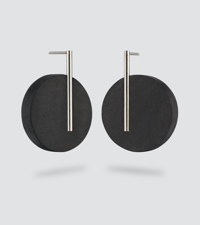 These bold statement earrings feature concrete discs that create a striking, sculptural presence while remaining surprisingly lightweight and comfortable for extended wear. The modern geometric design with sleek stainless steel accents offers a sophisticated contrast of textures and finishes, combining the raw, industrial appeal of concrete with polished metal. Their durable construction ensures longevity—stainless steel resists tarnishing while the concrete develops unique character over time