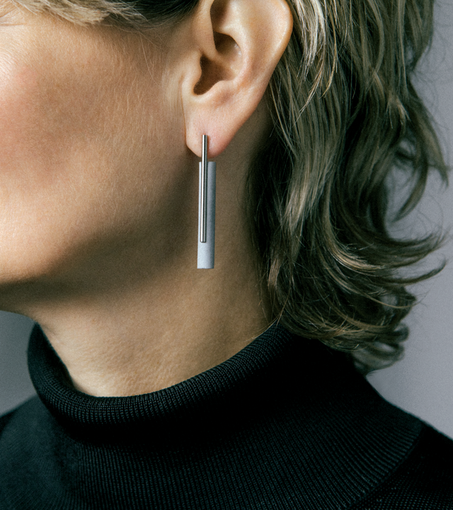 These elegant concrete and stainless steel drop earrings combine industrial materials in a sleek, minimalist design that offers both style and durability. The lightweight concrete cylinders provide unique texture and visual interest while remaining comfortable for extended wear, complemented by the corrosion-resistant stainless steel components that maintain their lustrous finish over time. Their understated linear silhouette makes them versatile everyday pieces that pair well with any wardrobe. The distinc