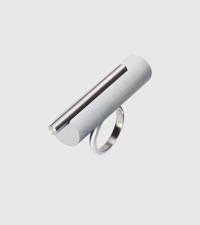 A minimalist tandem ring with a brushed stainless steel pillar and a small concrete pillar.