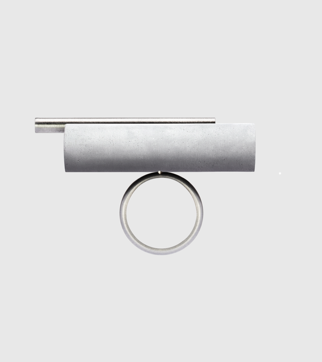 This striking Unity Tandem ring features a cylindrical concrete element set within a sleek stainless steel band, creating a bold architectural statement piece. The combination of industrial materials offers exceptional durability—stainless steel is highly resistant to tarnishing and corrosion, while concrete provides unique texture and character that develops beautifully over time.