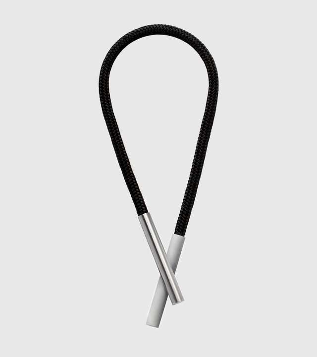 This striking statement necklace features sleek concrete and stainless steel elements suspended from a black cord, creating a bold yet minimalist aesthetic that draws the eye to the neckline. The innovative design uses rare earth magnets to attach the concrete and stainless steel components, allowing for versatile styling and effortless wear while ensuring secure placement.