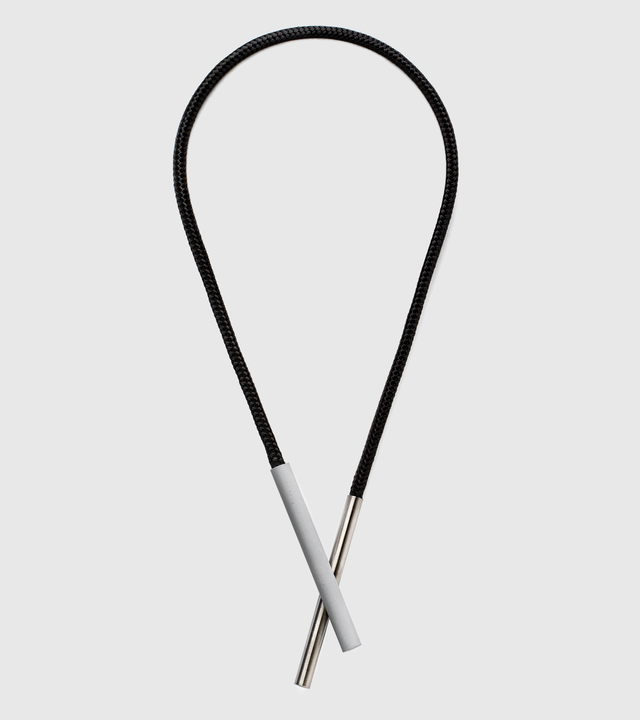 This sleek necklace features contrasting concrete and stainless steel cylinders elegantly suspended from a stainless steel cable, creating a refined minimalist statement. The architectural pairing of materials offers both visual interest and exceptional durability—the stainless steel resists tarnishing and maintains its lustrous finish, while the concrete provides unique texture that adds organic character.