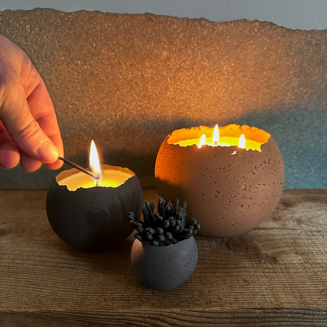orbis candles are sitting with a small orbis vessel holding black matches