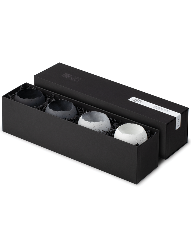 Four concrete vessels in shades of grey are displayed in a luxurious box set.