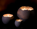 Three concrete Orbis candle holders with lit candles on a dark background. Medium, large and XL in charcoal