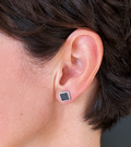 Close-up of model’s ear wearing unique stainless steel square stud earrings with inlaid concrete.