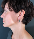 Model showcases modern geometrically shaped stainless steel stud earring inspired by Bauhaus designer Anni Albers.