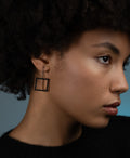 a model wearing simple and minimal black square drop earrings from the KONZUK Artus collection
